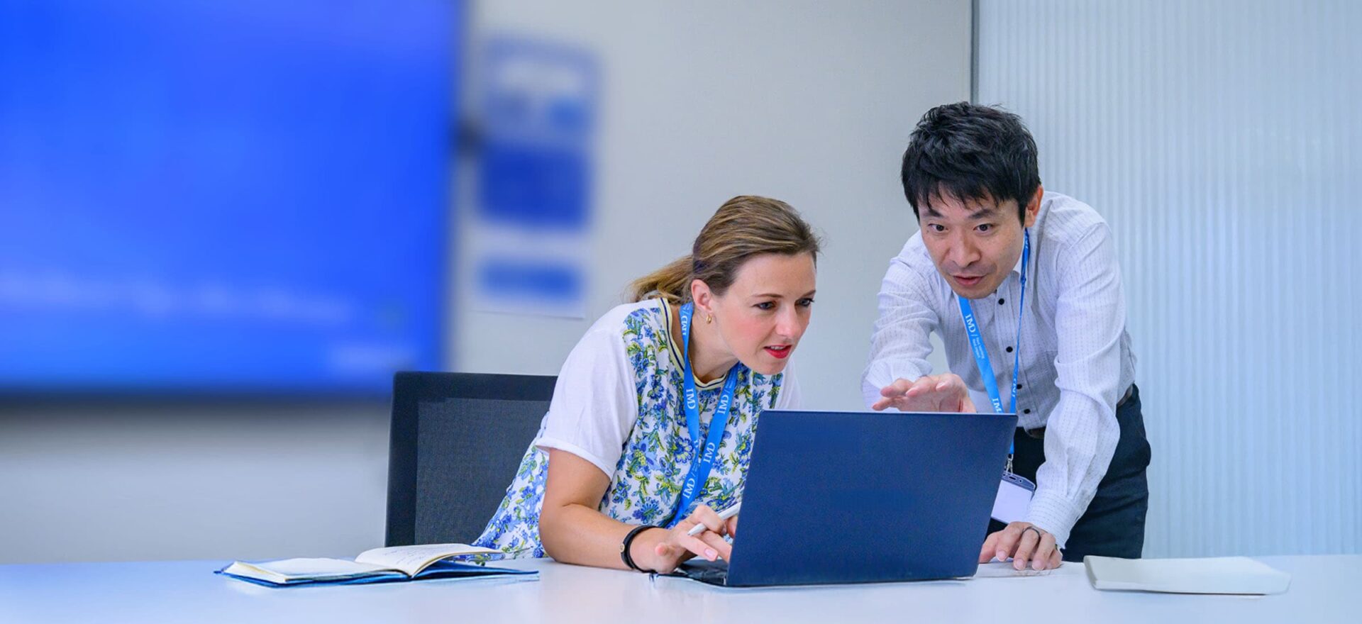 Professional executives engage in a strategy session with digital tools, representing AI and digital business transformation. - IMD Business School